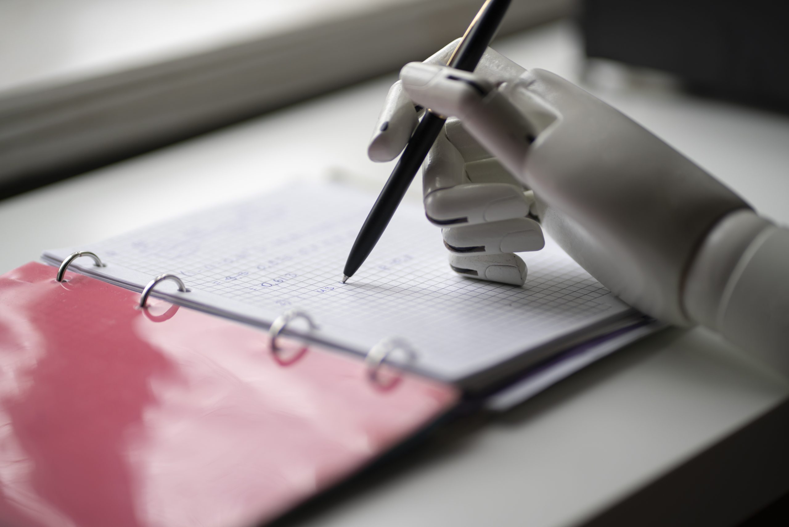 artificial robotic arm write down some notes with pen