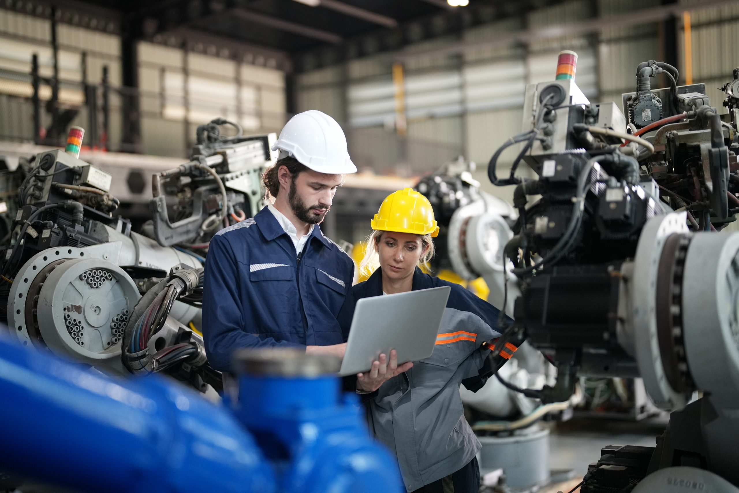 Engineer inspecting automatic robot arms and machines in factory.