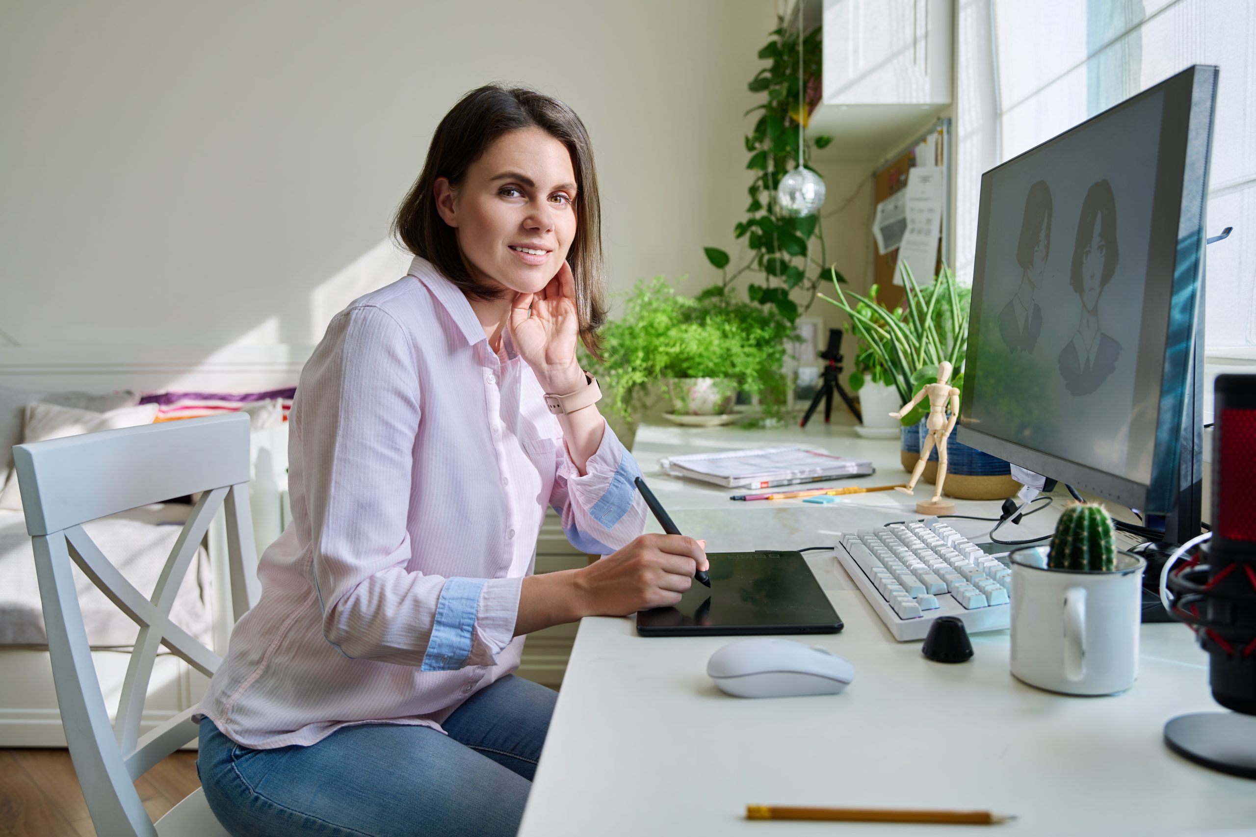 Portrait of young woman graphic designer looking at camera, female drawing sketch on graphic tablet, sitting in home office, freelancer working remotely. Designer creating characters for illustration